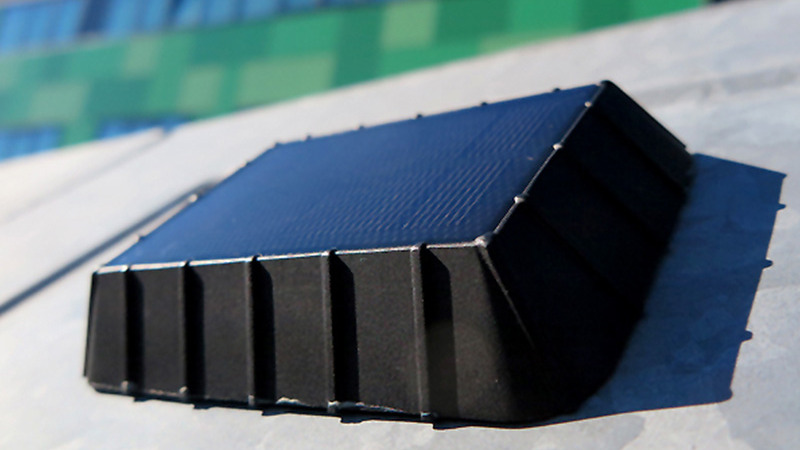 Abgebildet ist ein Sensorsystem, das auf einem grauen Abfallcontainer befestigt ist. Sichtbar ist eine schwarze Kiste, die auf der Deckfläche mit Solarmodulen ausgestattet ist.