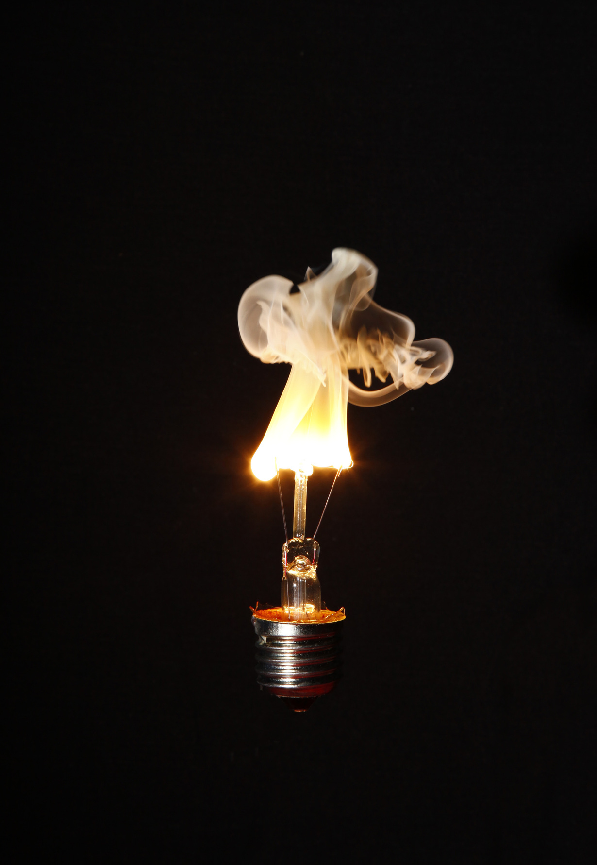 Glühbirne mit brennendem Streichholz anstelle eines herkömmlichen Glühdrahts vor dunklem Hintergrund